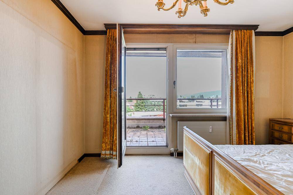 Schlafzimmer mit Teppichboden, Bett und direktem Zugang zu einem kleinen Balkon.