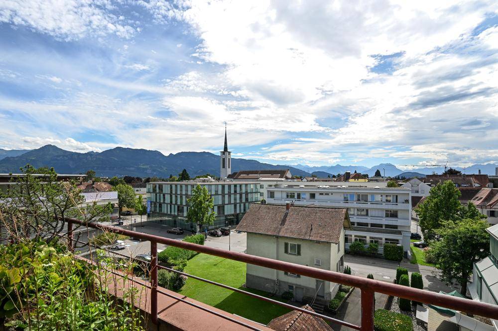 Panoramablick von der Immobilie auf die umliegende Stadt, eine Kirche und die majestätischen Berge.