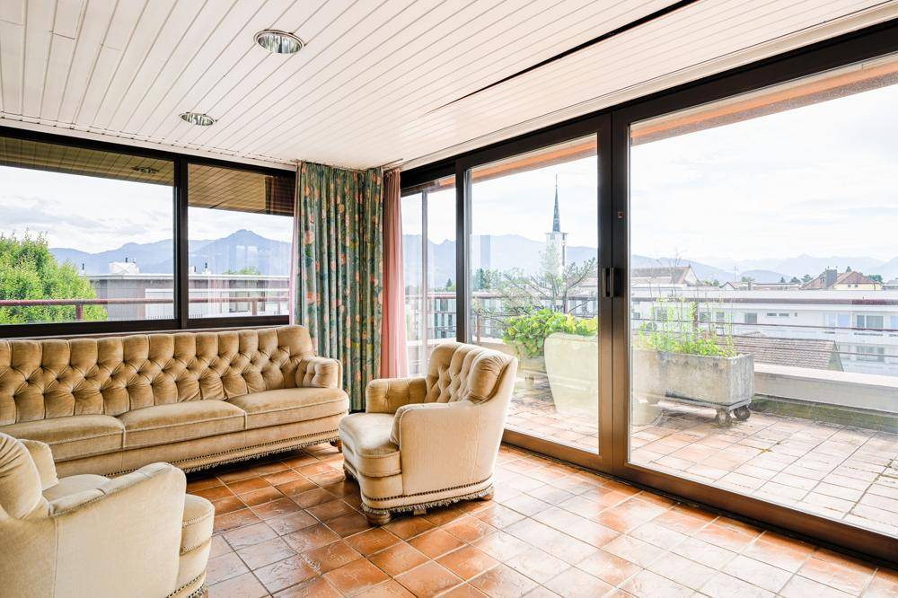 Helles Wohnzimmer mit großen Schiebetüren zur Terrasse und beigen Vintage-Sitzmöbeln.