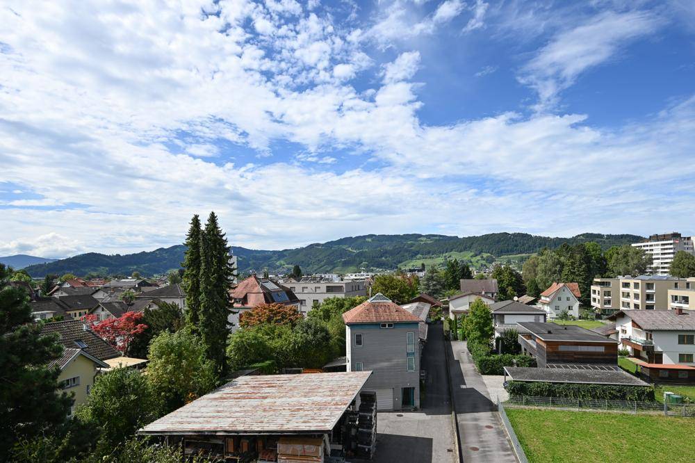 Blick über eine ruhige Wohngegend mit vielen Häusern und grünen Hügeln im Hintergrund.