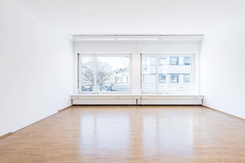 Große Fensterfront in einem hellen Raum, die viel Tageslicht hereinlässt und einen Blick nach draußen bietet.