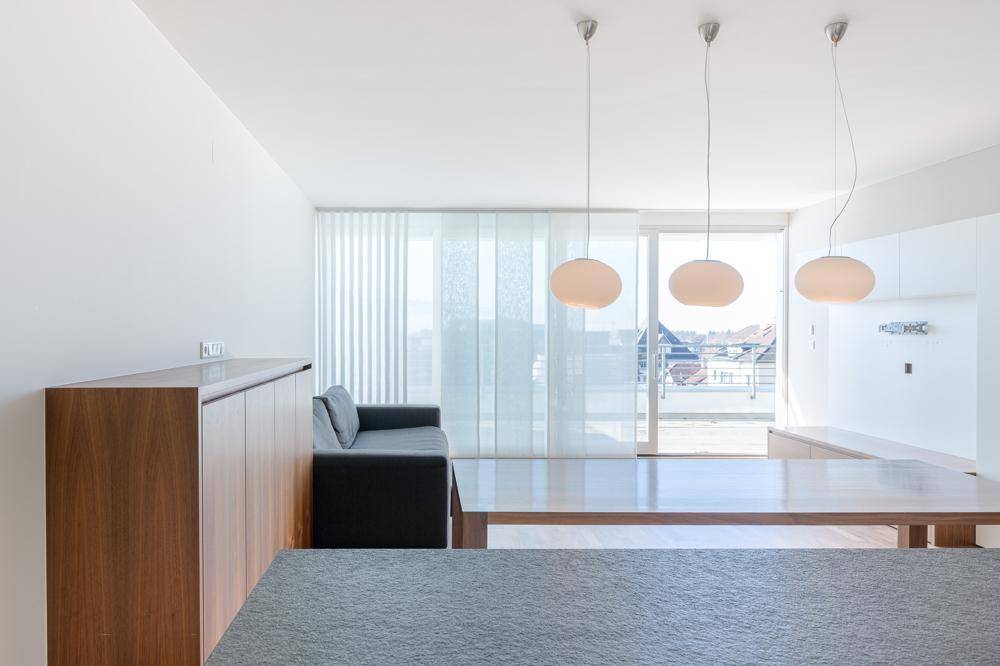 Lichtdurchfluteter Wohnbereich mit Zugang zur Terrasse und eleganten Pendelleuchten.