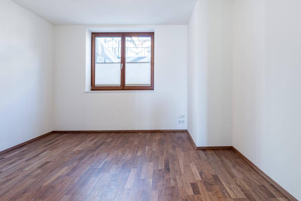 Helles Zimmer mit Holzboden und einem Fenster, das viel Tageslicht hereinlässt.