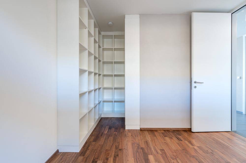 Zimmer mit großen, weißen Einbauregalen und Holzboden, ideal als Büro oder Bibliothek.