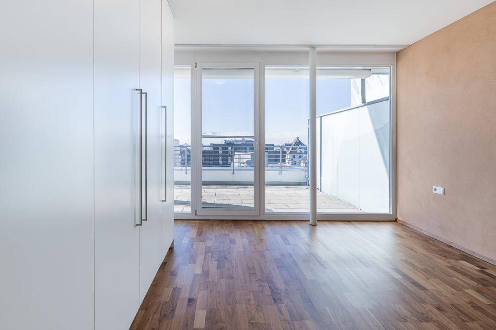 Geräumiges Schlafzimmer mit Einbauschränken, Holzboden und direktem Zugang zur Terrasse.