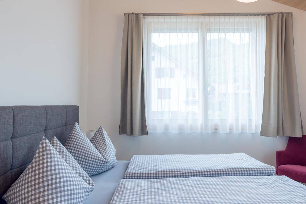 Helles Schlafzimmer mit bequemen Betten und Blick durch das Fenster auf die Umgebung.
