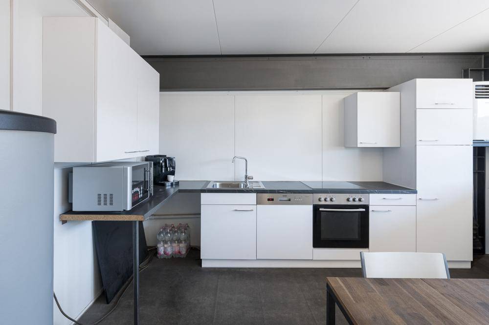 Funktionale Küchenzeile mit weißen Schränken, Induktionskochfeld, Backofen und integriertem Geschirrspüler.