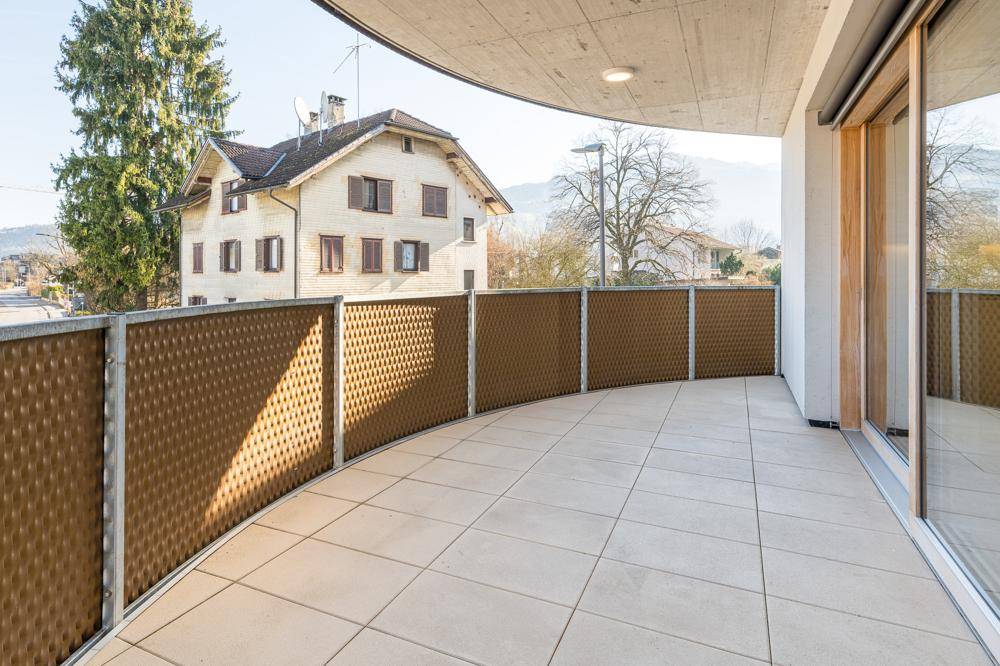 Geräumiger Balkon mit Fliesenboden und Blick auf die Umgebung und ein älteres Gebäude.