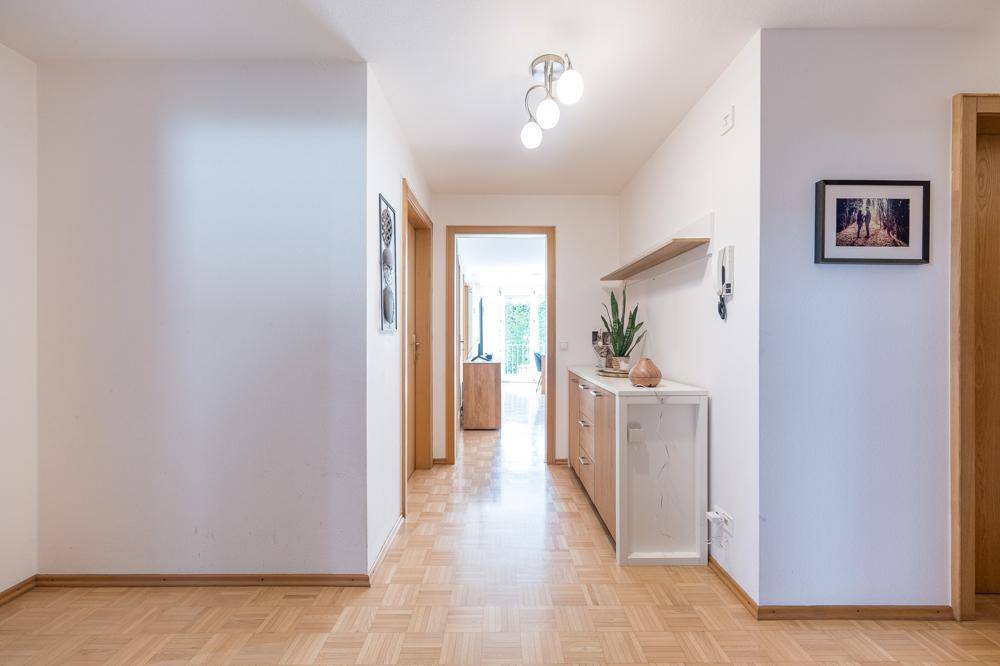 Heller Flur mit Parkettboden und Zugang zu verschiedenen Zimmern.
