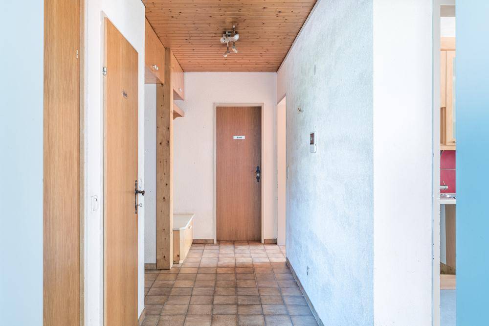 Geräumiger Flur mit Fliesenboden, Holzdecke und integrierten Ablagemöglichkeiten.