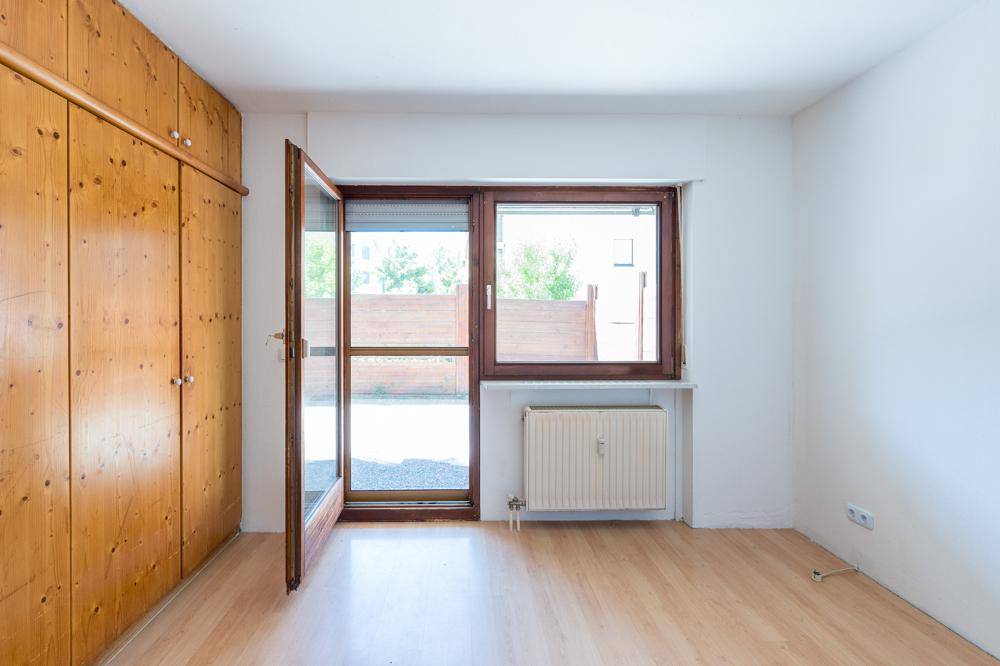 Helles Schlafzimmer mit Laminatboden, großem Fenster und praktischem Einbauschrank.
