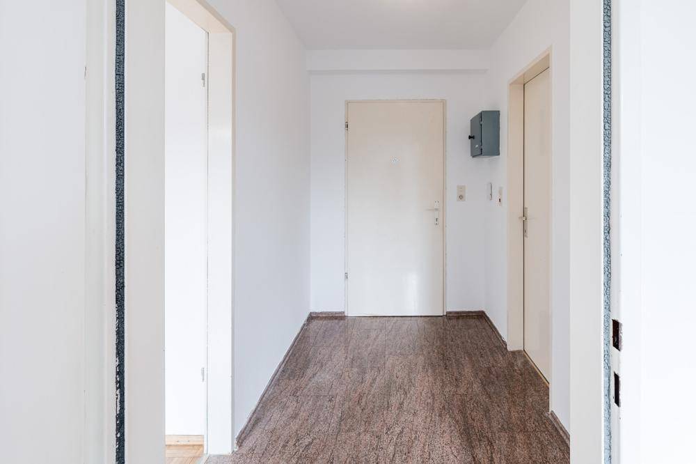 Heller Flur mit dunklem Fliesenboden und Zugang zu verschiedenen Räumen.