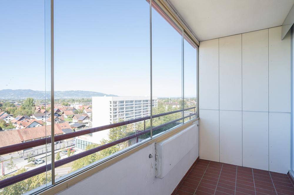 Verglaster Balkon mit Terrakotta-Fliesenboden und weitem Blick über die Stadt und die Umgebung.