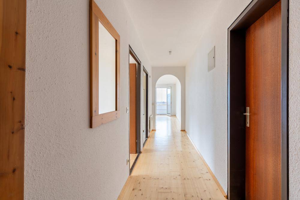 Heller Flur mit Holzfußboden und mehreren Türen, der zu weiteren Räumen führt.
