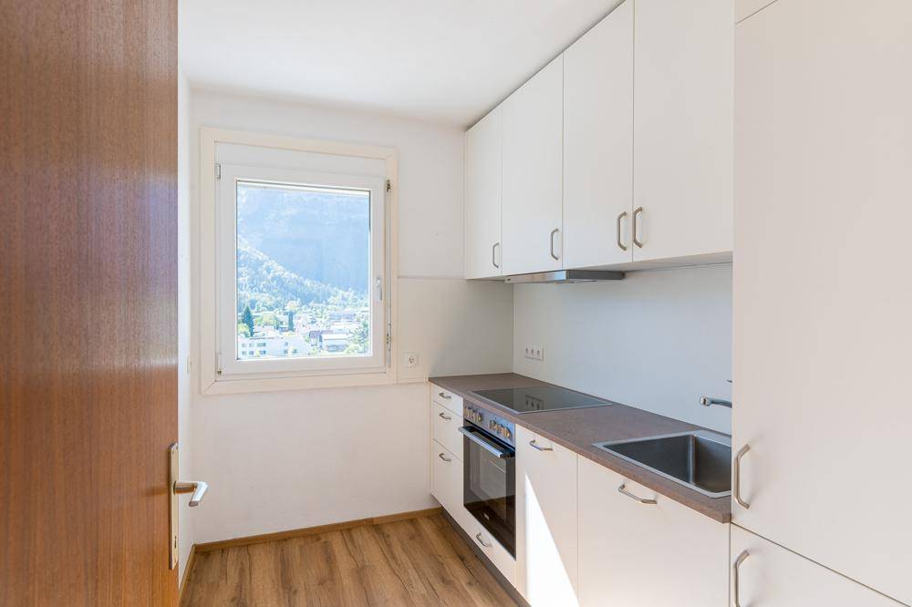Funktionale Küche mit weißen Schränken, Einbaugeräten und Blick auf die umliegende Berglandschaft.
