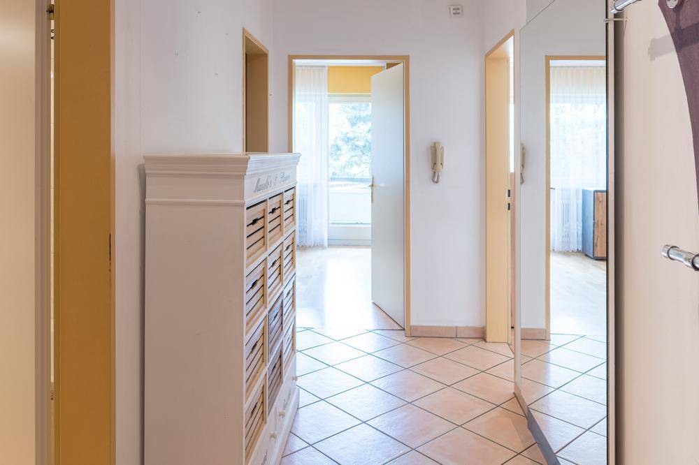 Heller Flur mit Fliesenboden, Spiegelschrank und Zugang zu weiteren Räumen.