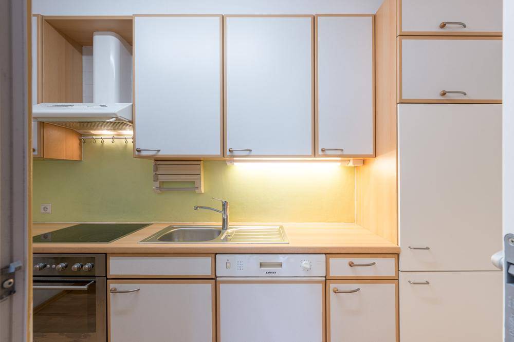 Funktionale Küche mit weißen Schränken, Holztheke und integrierten Geräten.
