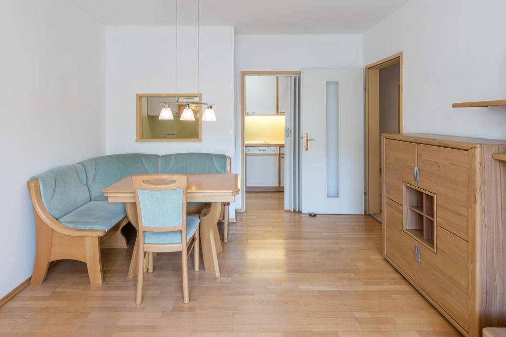 Gemütlicher Essbereich mit Eckbank, Holztisch und Durchreiche zur Küche.