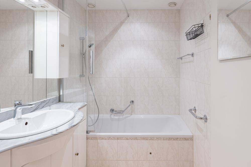 Modernes Badezimmer mit Badewanne, Duschvorrichtung und Marmorwaschtisch.