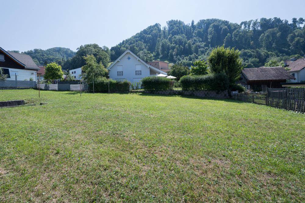 Weitläufige Rasenfläche mit Blick auf bewaldete Hügel und weitere Wohnhäuser in der Ferne.