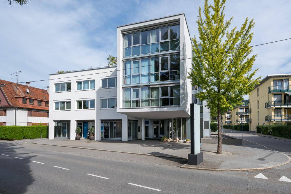 Modernes Geschäftsgebäude mit großer Glasfassade und klaren Linien an einer belebten Straße.