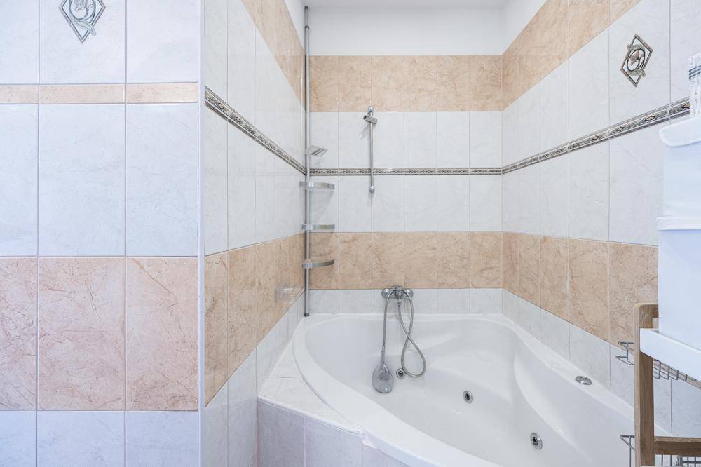 Badezimmer mit Eckbadewanne und hellen Fliesen, bietet Entspannung.
