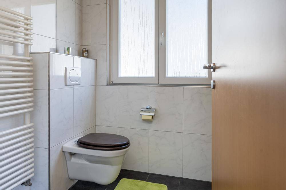 Separates WC mit Wand-WC, Fenster und beheiztem Handtuchhalter.