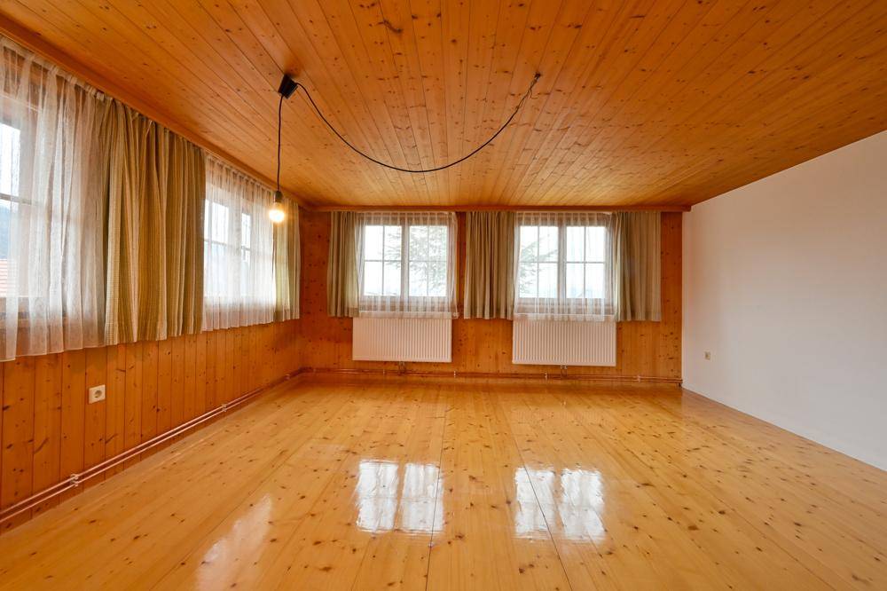Geräumiges Zimmer mit Holzboden, Holzdecke und mehreren Fenstern für viel Tageslicht.