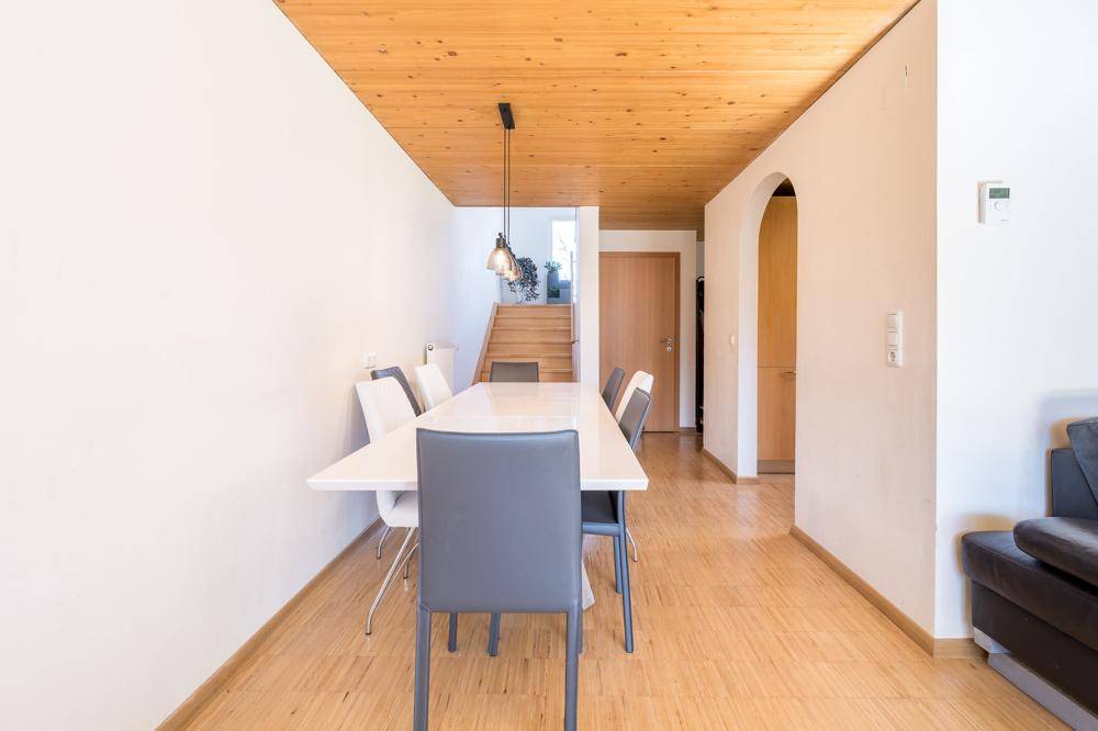 Heller Essbereich mit Holzbalkendecke, Parkettboden und Zugang zur Treppe.