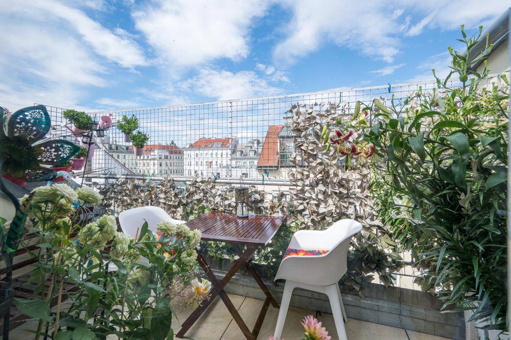 Kleiner Balkon mit Sitzgelegenheiten und üppiger Bepflanzung, bietet einen Blick über die Stadt.