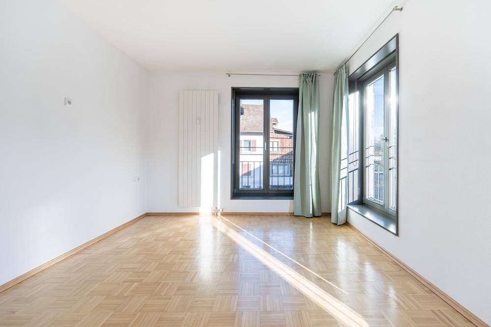 Heller Raum mit Parkettboden, großen Fenstern und viel natürlichem Licht.