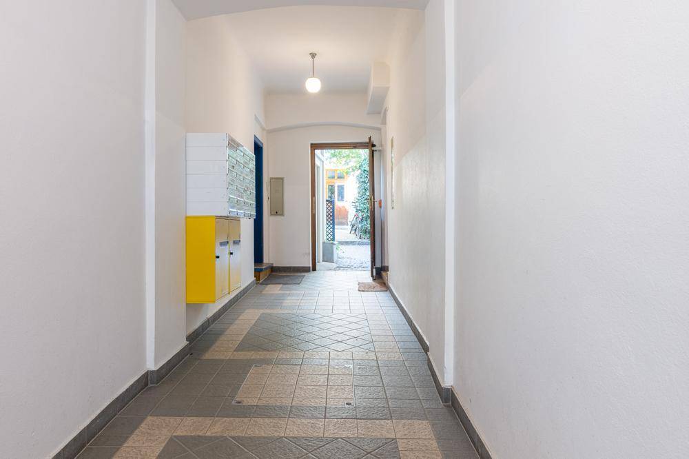 Gemeinschaftlicher Eingangsbereich mit Fliesenboden und Briefkästen, führt zum Hof.