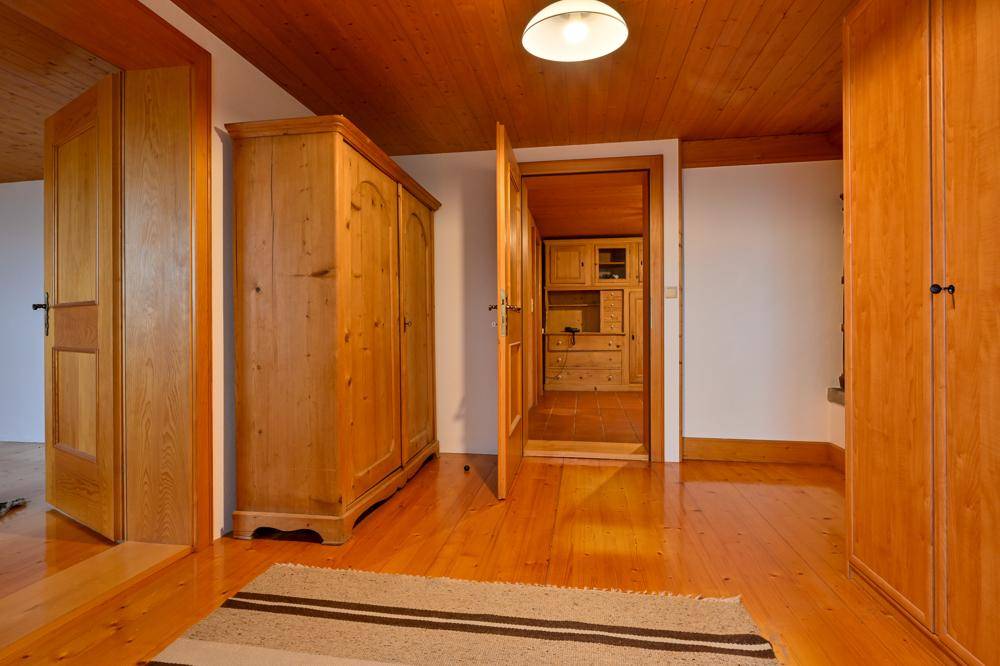 Heller Flur mit Holzboden, Holzdecke und einem traditionellen Holzschrank.