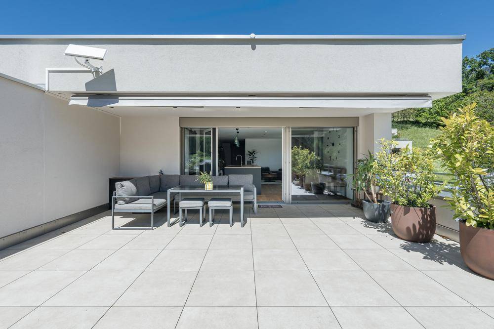 Geräumige Terrasse mit modernen Gartenmöbeln und Blick auf den Innenbereich des Hauses.