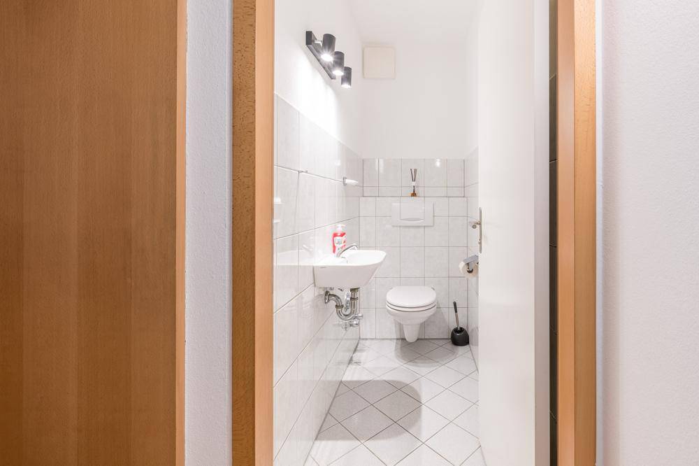 Kleines Gäste-WC mit Waschbecken, Toilette und weißen Wandfliesen.