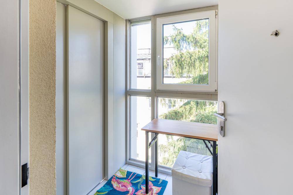 Heller, verglaster Loggia-Bereich mit kleinem Tisch und Blick ins Grüne.