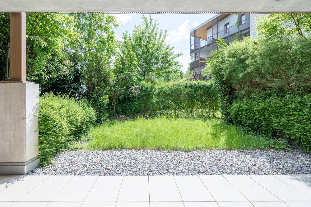 Kleiner privater Gartenbereich mit Rasenfläche und Kiesweg, umgeben von Hecken.