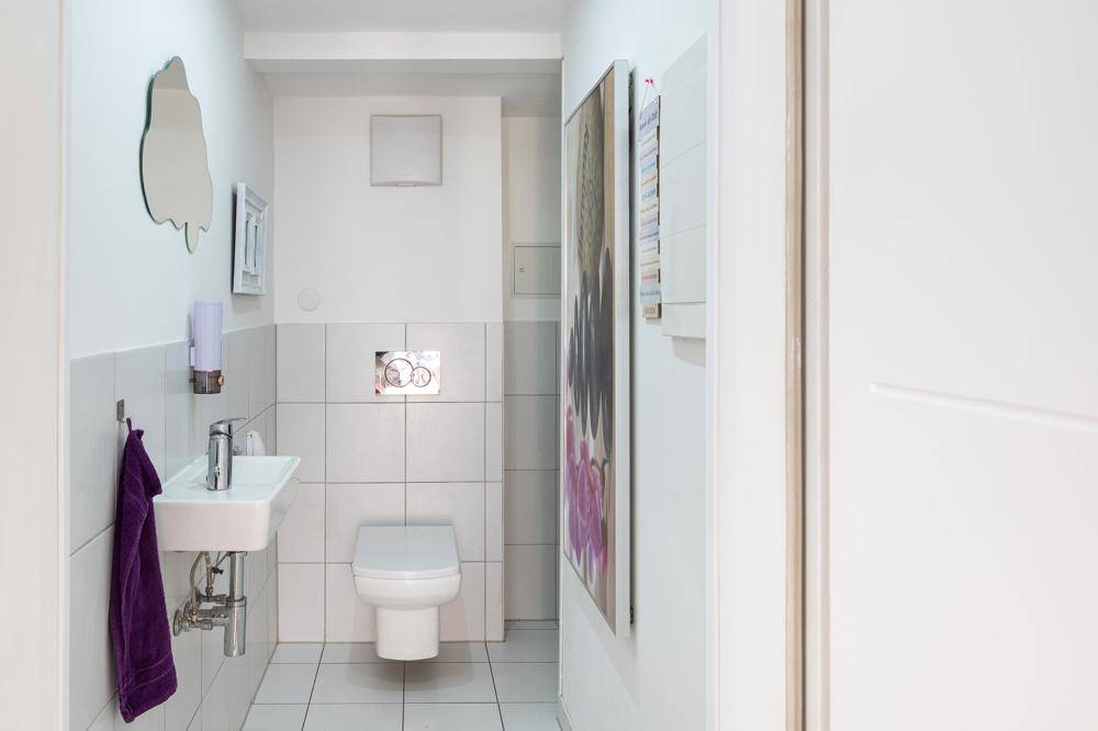 Modernes Gäste-WC mit wandhängender Toilette und kleinem Waschbecken.