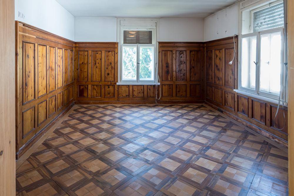 Zimmer mit Holztäfelung an den Wänden und gemustertem Parkettboden.