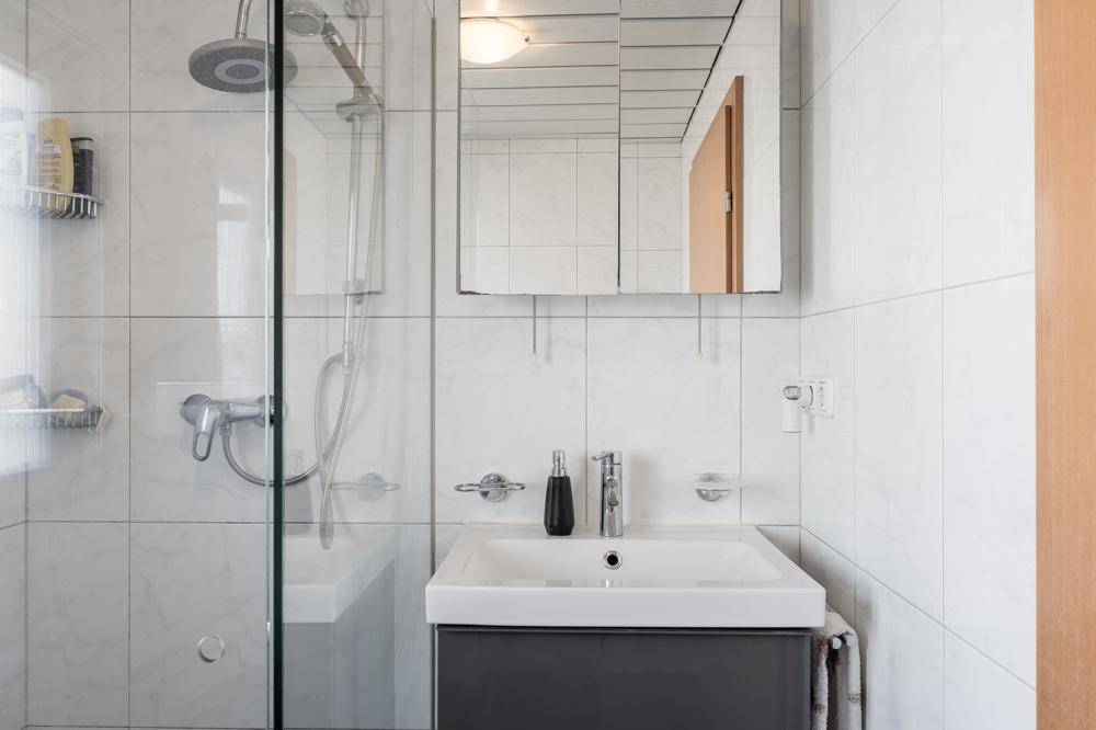 Modernes Badezimmer mit Duschkabine, Einzelwaschbecken und Spiegelschrank.