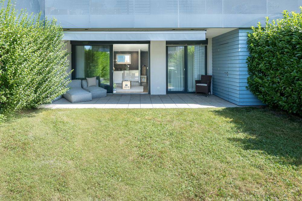 Sonniger Außenbereich mit gepflasterter Terrasse, Rasenfläche und direktem Zugang zum Wohnraum.