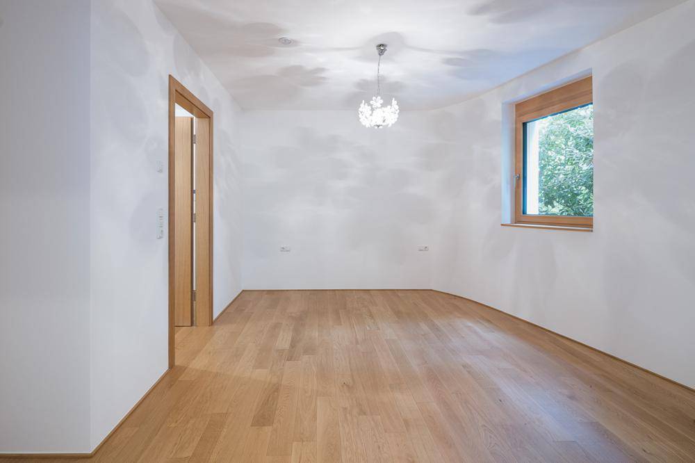 Geräumiges, helles Zimmer mit Parkettboden und einem Fenster mit Blick nach draußen.