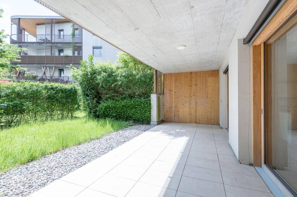 Überdachte Terrasse mit Fliesenboden und Zugang zum Gartenbereich.