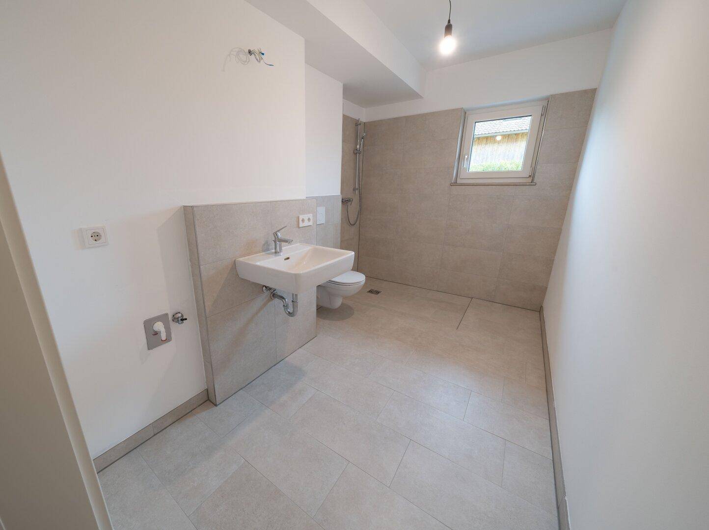 Modernes Badezimmer mit Dusche, Waschbecken, WC und einem Fenster für natürliche Belüftung.