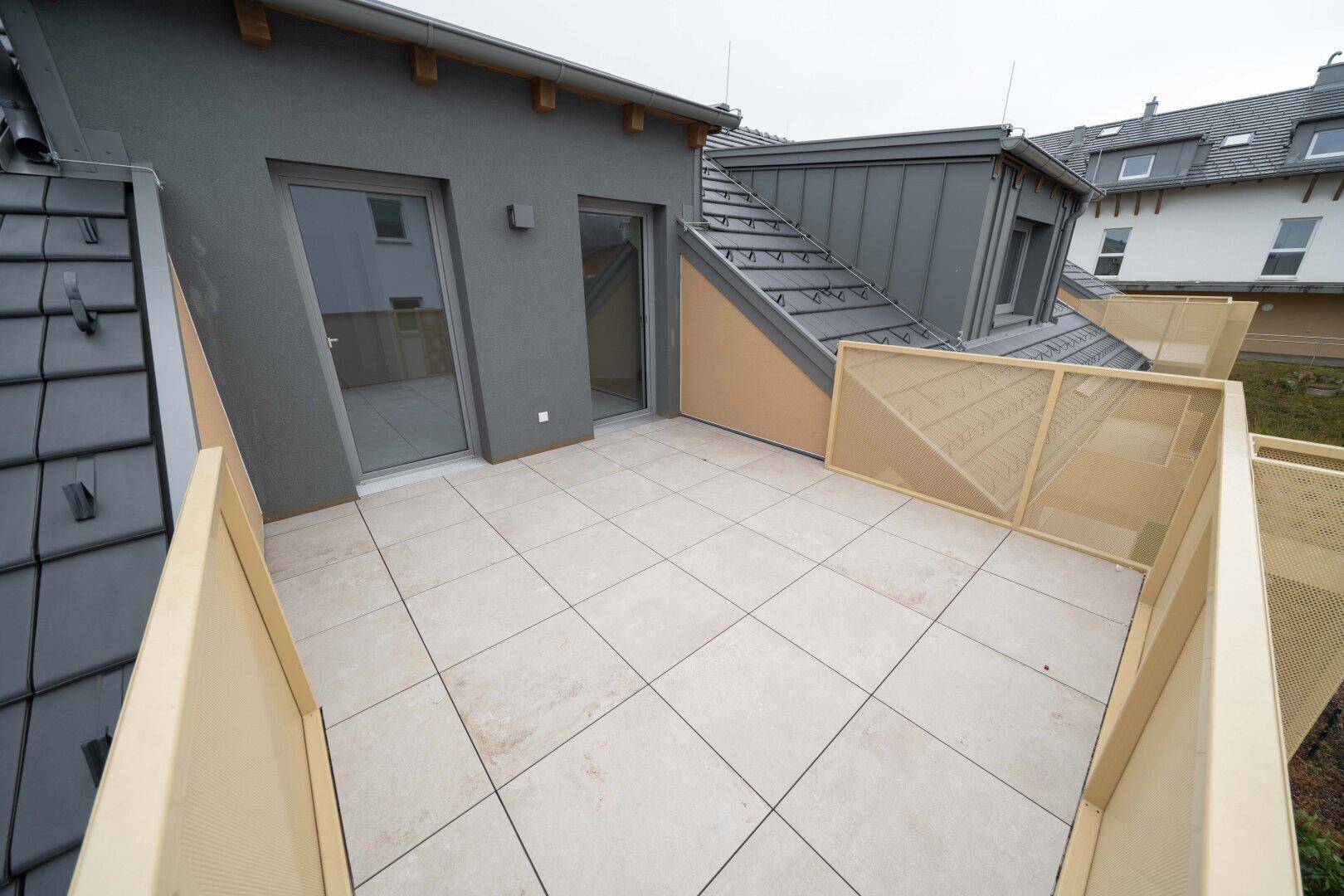 Geräumige Dachterrasse mit modernen Fliesen und Zugang zu den Innenräumen.