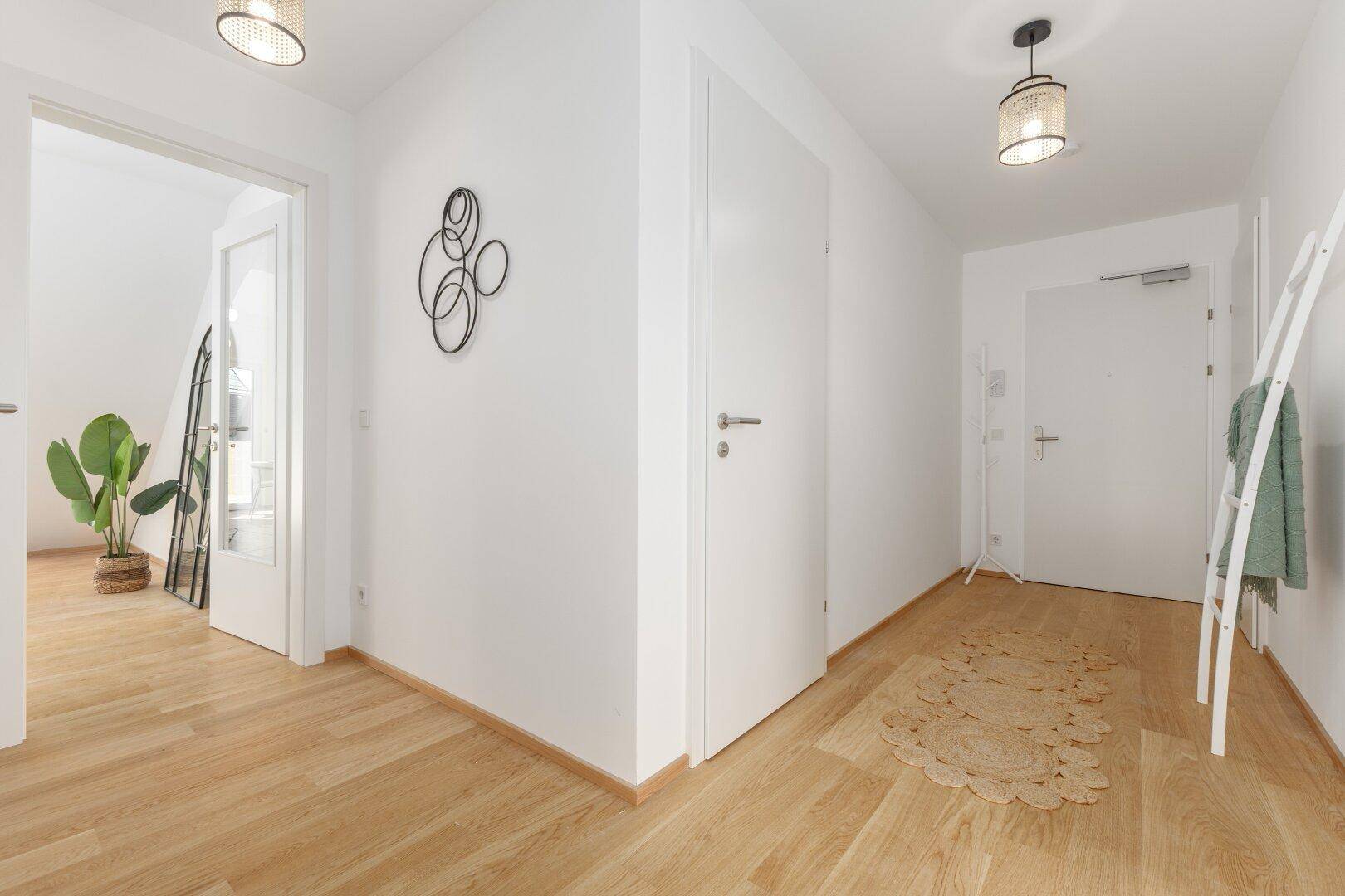 Heller Eingangsbereich mit Holzfußboden und modernen Leuchten.