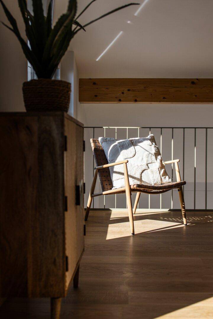 Detailansicht eines Sessels und einer Pflanze auf der sonnigen Galerie.