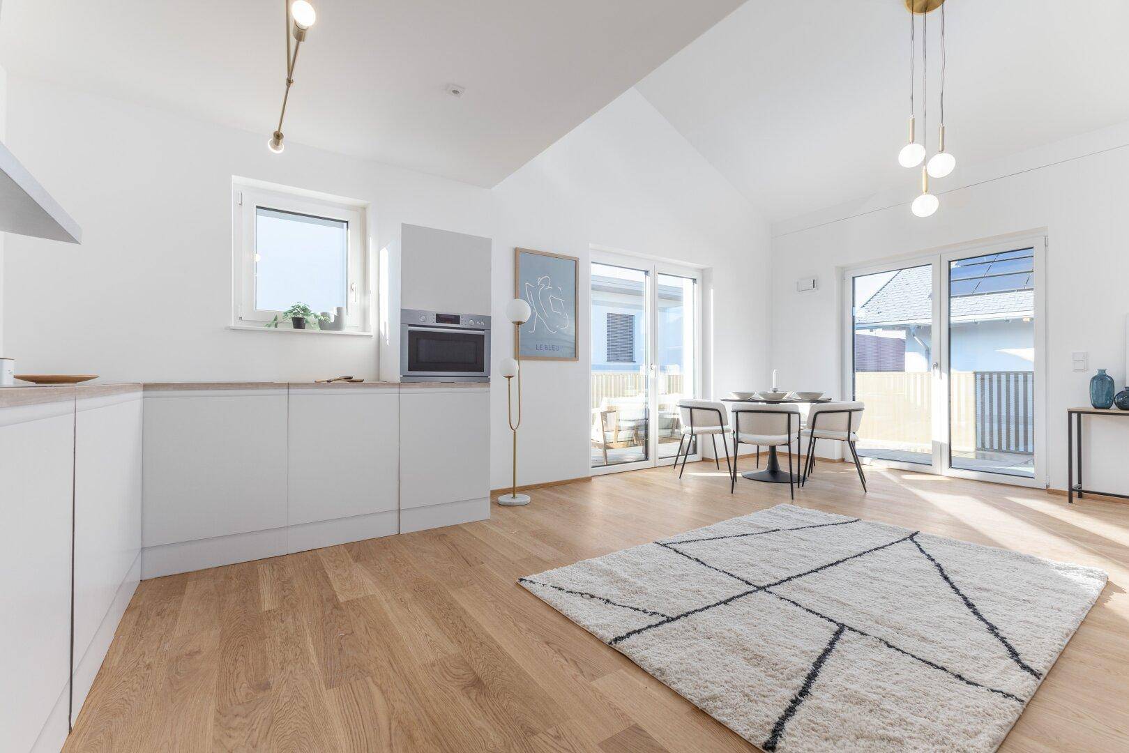 Moderne Küche mit Essbereich, Holzboden und Zugang zu einem Außenbereich.