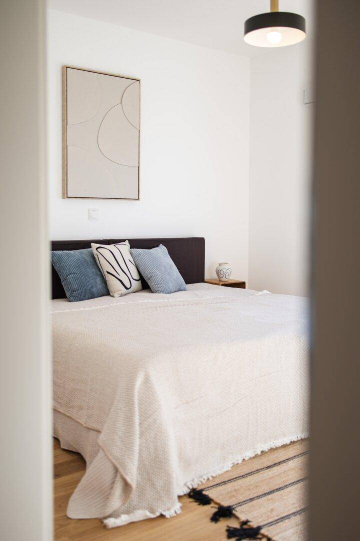 Gemütliches Schlafzimmer mit Holzboden und modernem Kunstwerk an der Wand.