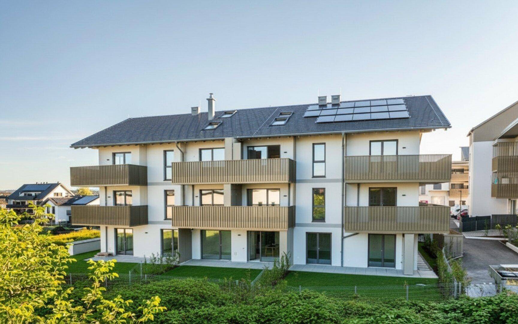 Neubauwohngebäude mit Balkonen, Photovoltaikanlage und gepflegter Außenanlage.